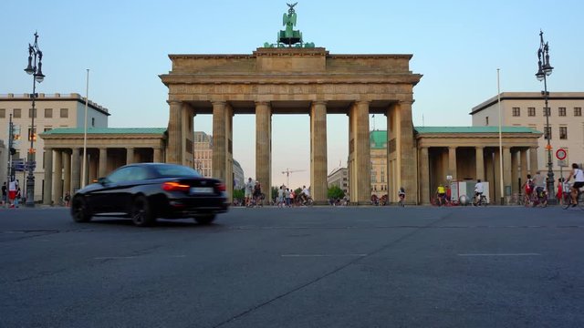 The Front Of The Brandenburg Gate With Cars Driving By