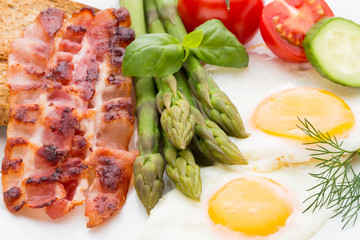 Fried eggs with bacon on the wooden table.