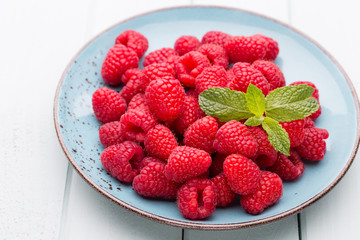 Fresh raspberries in a plate on a  vintage background.