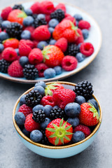 Fresh berry salad on blue dishes. Vintage wooden background.