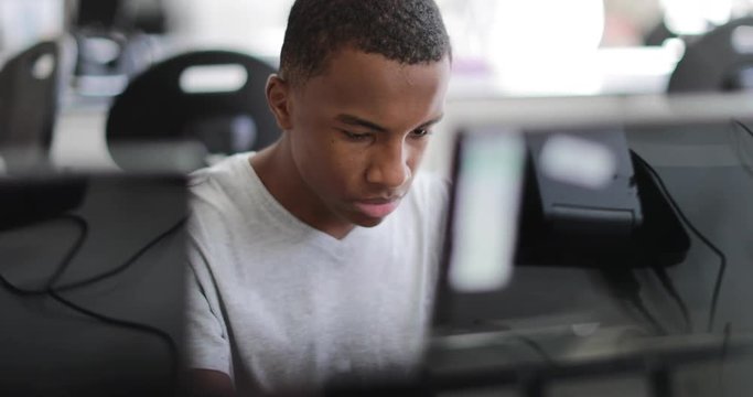Closeup teenage boy using a computer in class