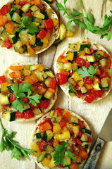 kleine Brötchenpizzen mit buntem Zucchini-Paprika Gemüse und Parmesan