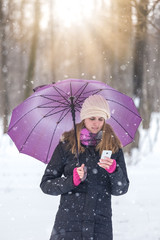 Portrait of beautiful young woman holding mobile phone on snowy day.