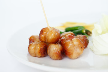 Grilled sausage ball on a white plate on white background.