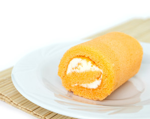 orange cake roll on white plate on wooden mat.