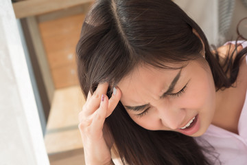 Fototapeta premium portrait of sick woman with headache; depressed woman suffers from stress, vertigo, dizziness, migraine, hangover; health care and mental health concept; 20s young adult asian woman model