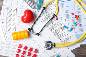 Flat lay composition with stethoscope and pills on table. Cardiology service