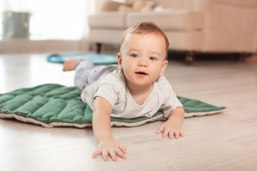 Adorable little baby crawling on floor at home