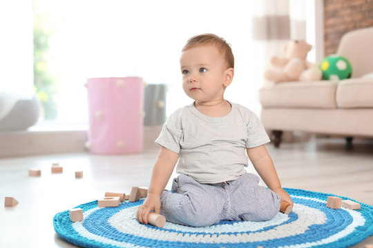 Adorable little baby playing with wooden blocks at home