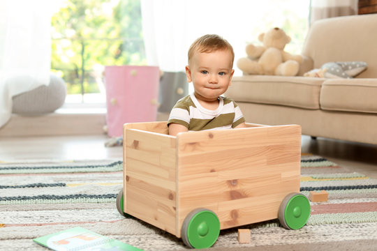 Adorable little baby in wooden cart at home