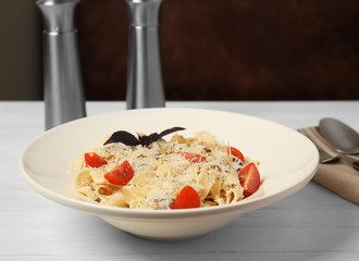 Delicious pasta with tomatoes and cheese on wooden table