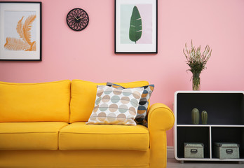 Modern living room interior with comfortable yellow sofa near color wall