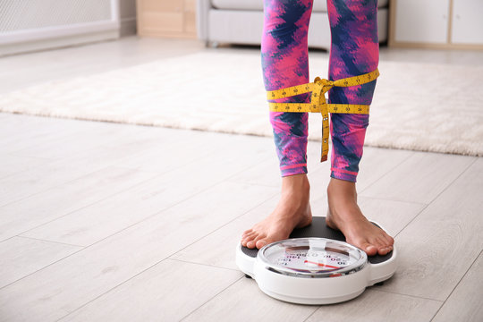 Woman tied with tape measuring her weight using scales on floor