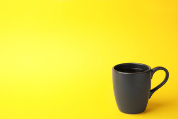 Black ceramic cup with hot aromatic coffee on color background