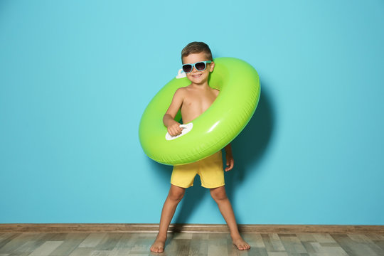 Cute little boy with inflatable ring near color wall