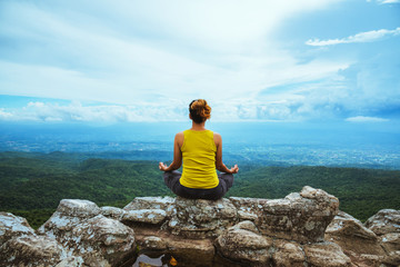 Asian woman relax in the holiday. Travel relax.  Play if yoga. On the Moutain rock cliff. Nature of mountain forests in Thailand