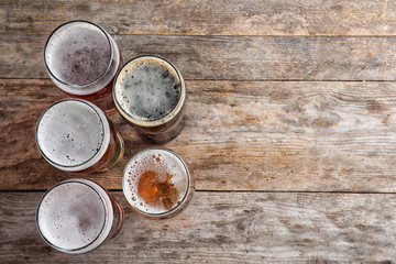 Glasses with different types of cold tasty beer on wooden background