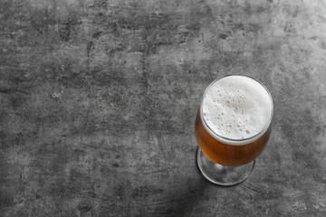 Glass with cold tasty beer on grunge background, view from above