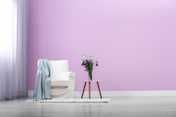 Stylish comfortable armchair near color wall