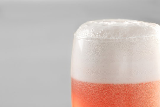 Glass of red tasty beer with foam, closeup