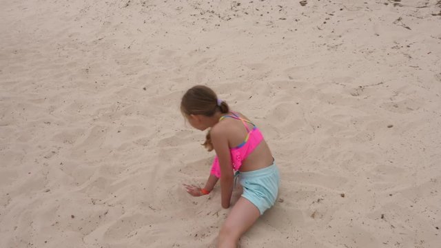 Adorable young girl breakdancing on sandy beach