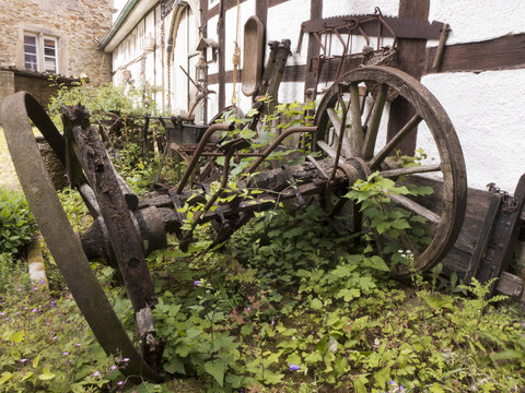 Alte Wagenräder und alte Ackergeräte verrotten auf einem Bauernhof