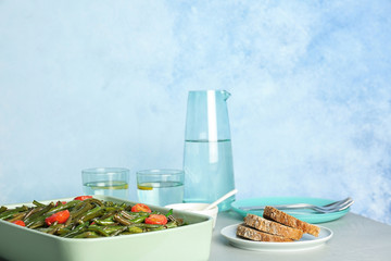 Dish with tasty green beans and tomatoes on table
