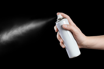 Hand using a spray, isolated on black background