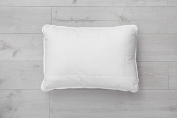 Clean soft bed pillow on wooden background, top view