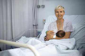 Mother breastfeeding her newborn baby boy in the hospital