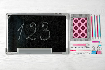 Flat lay composition with different school stationery and small chalkboard on wooden background