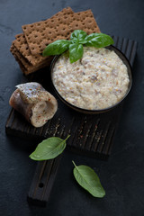 Black wooden serving board with a bowl of herring forshmak, studio shot, selective focus