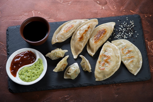 Stone slate tray with fried korean dumplings including potstickers and wontons, selective focus