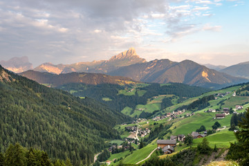 Morning mountain landscape during sunrise in the Dolomites in South Tyrol: sunlit mountain peak called Peitlerkofel seen from a valley in La Valle