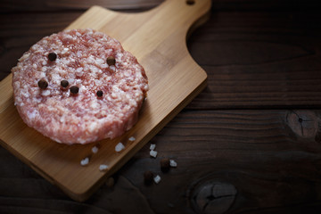 Raw minced meat for burger on wooden cutting plank