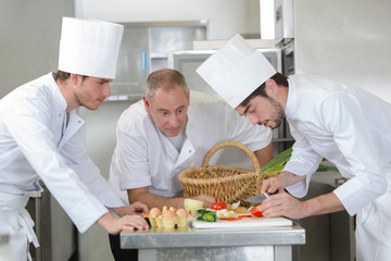 chief chef watching his assistants garnishing a dish