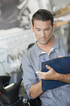 Mechanic making notes on clipboard