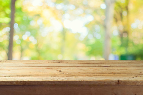 Empty wooden table over autumn nature bokeh background