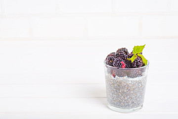 Food and drink, healthy eating and dieting concept. Homemade white chia pudding with fresh berries and green leaves for breakfast on a light kitchen table. Copy space.