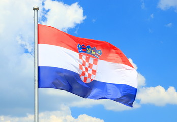 Fototapeta na wymiar Croatian flag flying on wind, blue sky with clouds in background