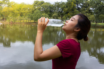 Athlete woman breaks and drinking water after running in the park, healthy concept