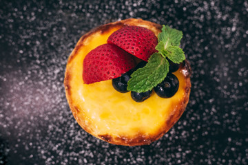 Fototapeta na wymiar Close up Cheese tart topping with slices of strawberry and blackberry with icing sugar.