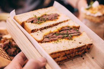 Close up of Japanese medium rare Wagyu sandwich served in wooden box.