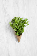 Waffle sweet ice cream cone with mint on white wooden surface, view from above. Top view.