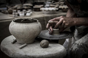 A raw clay pot in the hands of a potter. Workshop in the pottery workshop - obrazy, fototapety, plakaty