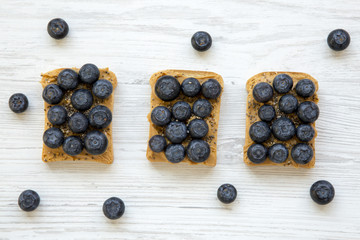 Vegan toasts with peanut butter, blueberries and chia seeds on a white wooden table, top view. Healthy eating. Flat lay, from above.