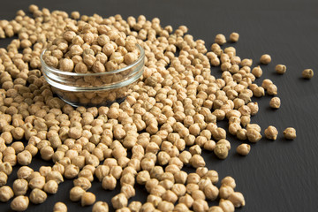 Dried chickpeas in bowl on black background, low angle. Closeup.