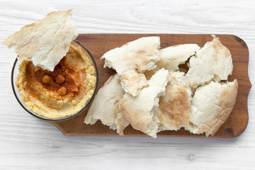 Bowl of Hummus with roasted chickpeas, paprika, olive oil and pita bread on rustic wooden board over white wooden table., top view. From above, overhead. Closeup.