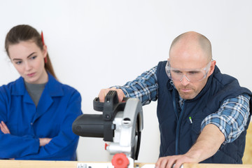 carpenter training female apprentice to use plane