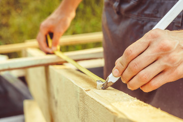 the worker makes measurements with a tape measure